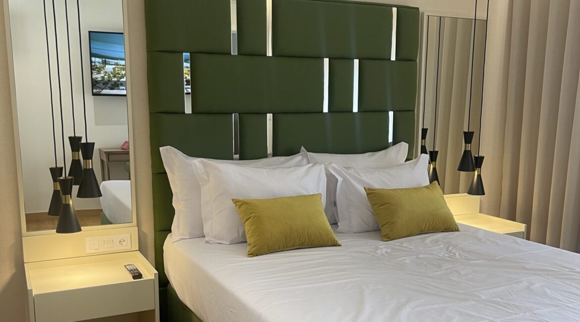 cama verde candeeiros e espelho num quarto design interiores